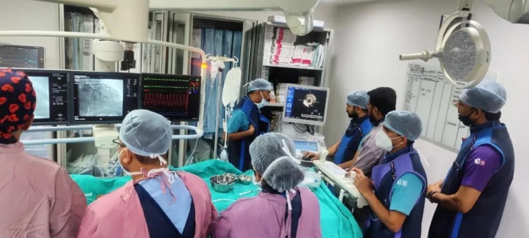 Dr. (Col) Ajay Bahadur performing a coronary angioplasty procedure using advanced imaging technology in a modern cath lab at Apollomedics Hospital, Lucknow.